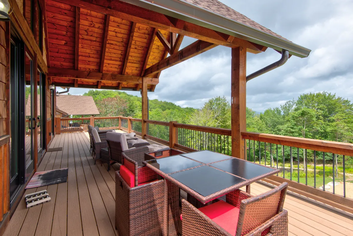 A cozy wooden deck set with a dining table and outdoor seating, nestled in a natural landscape. The setting is inviting for family gatherings, outdoor meals, or enjoying barbecues, with the backdrop of nature enhancing the sense of relaxation and togetherness.
