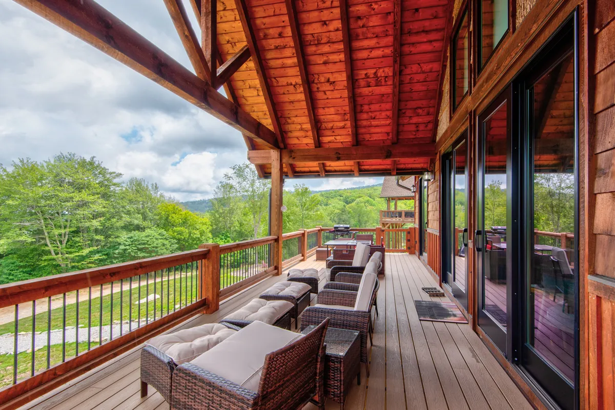 A cozy outdoor area featuring wooden beams, comfortable seating, a grill for outdoor dining, and a clear view of the mountains. The space encourages social gatherings or quiet moments, whether for barbecues, stargazing, or enjoying the changing light as day turns to night.